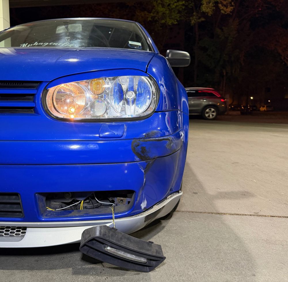 Frontschaden an einem blauen Kleinwagen, nachts an einer Tankstelle